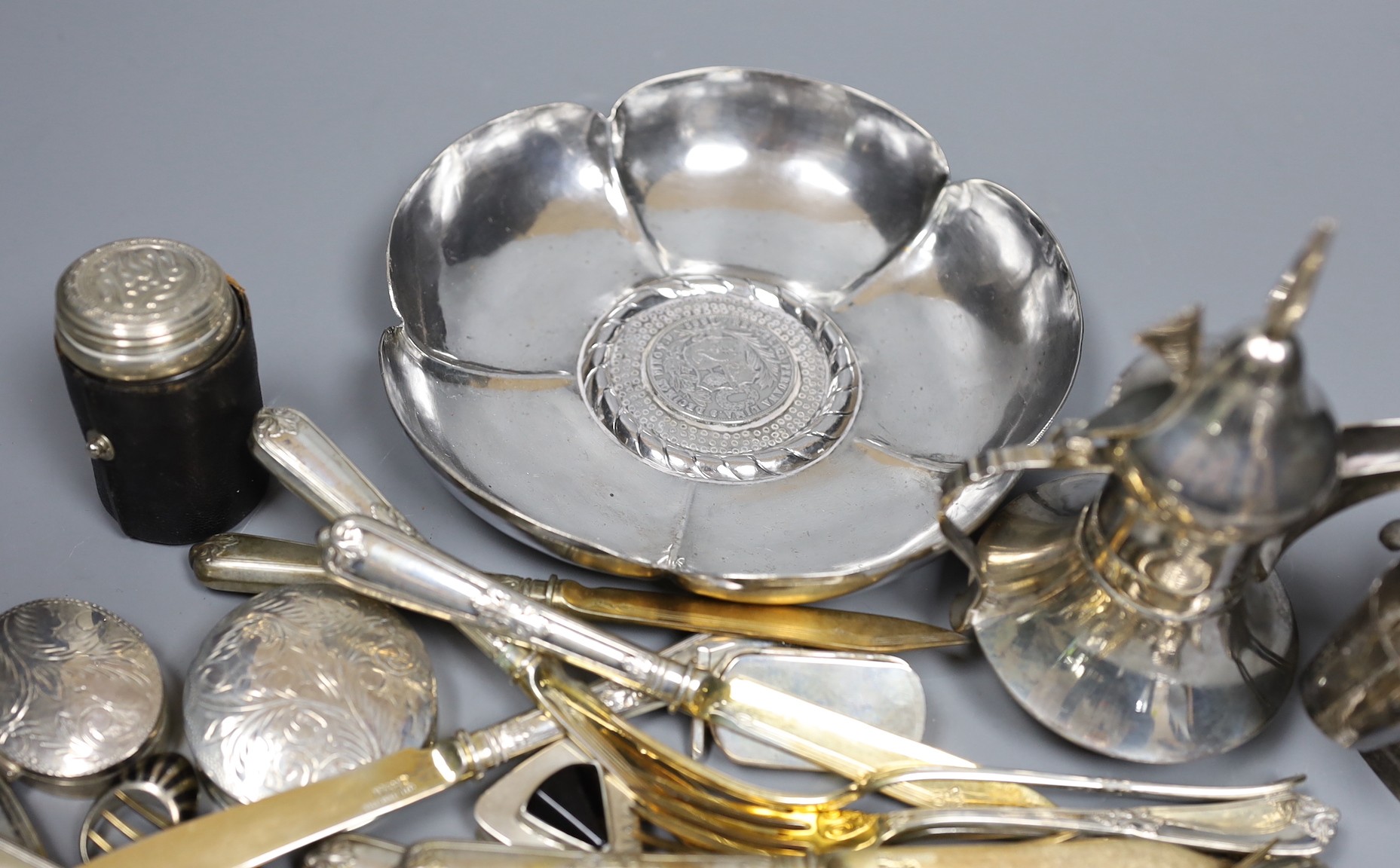 A Peruvian sterling dish with inset coin, an Egyptian white metal pill box, other 925 and white metal items including flatware, ring and sterling travelling beakers.